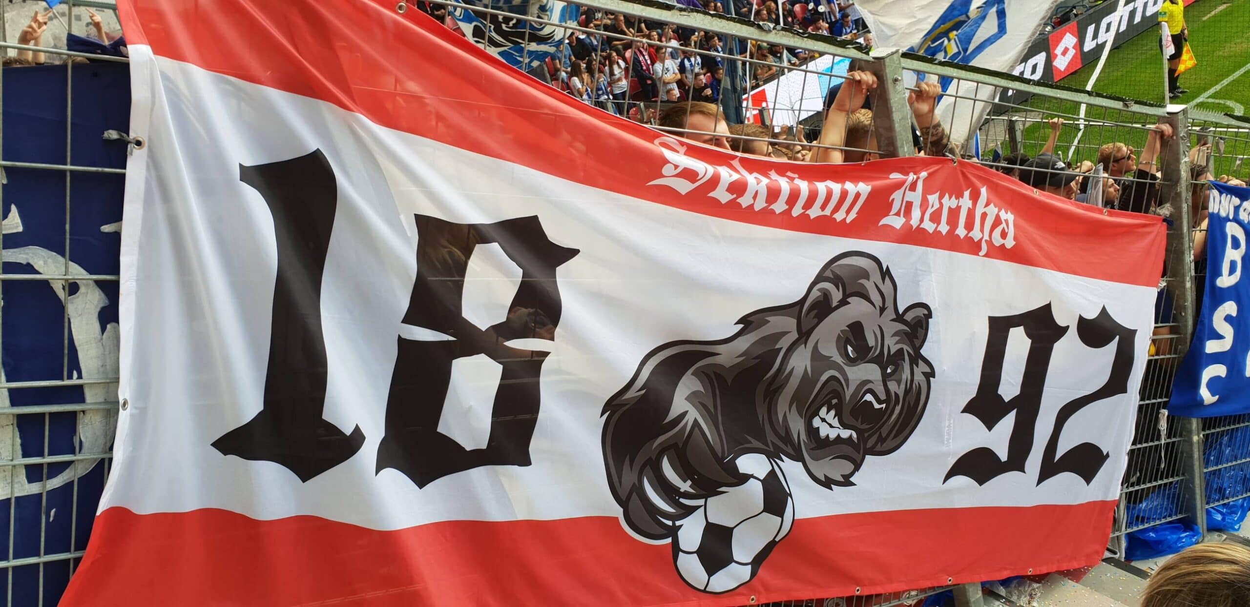 Ein Zaun mit einem Hertha-Fanbanner, Motiv: Bär mit Fußball, Aufschrift "1892".